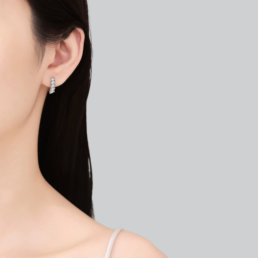 Emerald Cut Moissanite Huggie Hoop Earrings in Rhodium-Plated S925 sterling silver worn on ear by model showing scale, placement, and huggie hoop earrings styling
