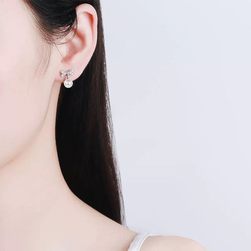 Bow Moissanite Stud Dangle Earrings in Rhodium-Plated S925 sterling silver worn on ear by model showing scale, placement, and stud dangle earrings styling