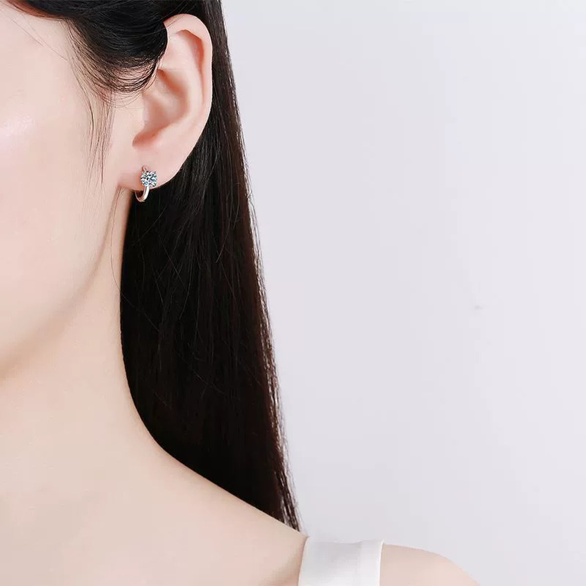 Round Moissanite Huggie Hoop Earrings in Rhodium-Plated S925 sterling silver worn on ear by model showing scale, placement, and huggie hoop earrings styling