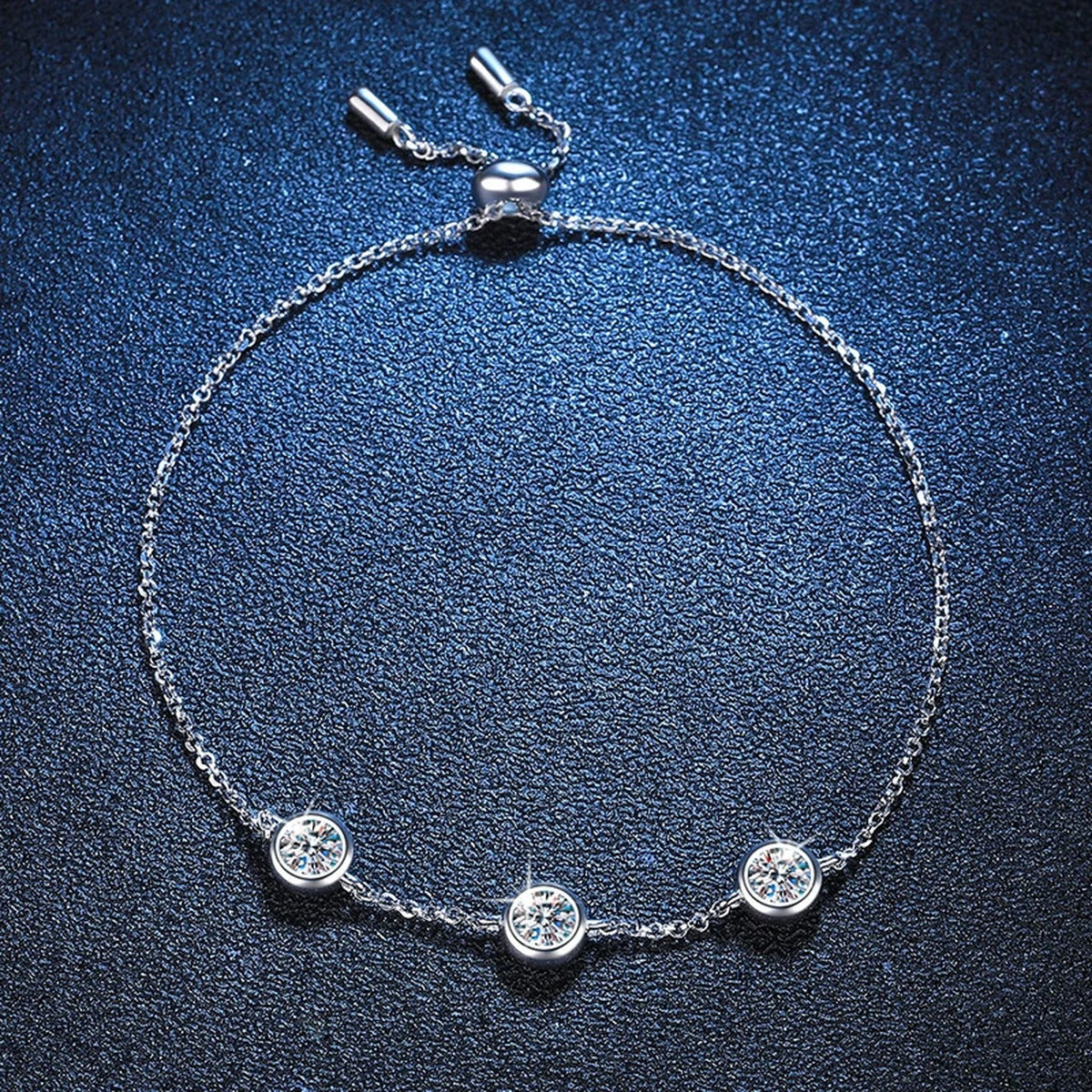 Three-Stone Moissanite Adjustable Station Bracelet styled on blue display background with visible moissanite sparkle