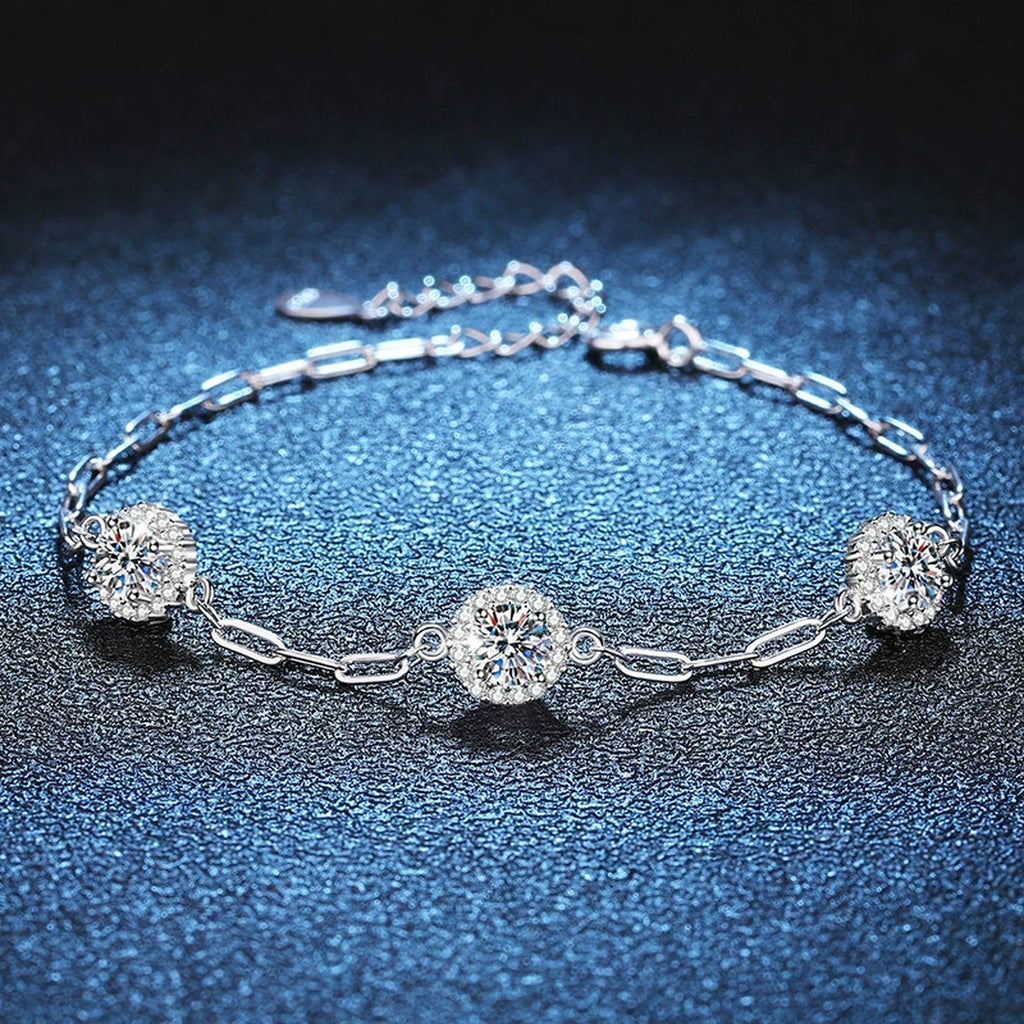 Three-Stone Round Moissanite Chain Bracelet with CZ styled on blue display background showing moissanite sparkle