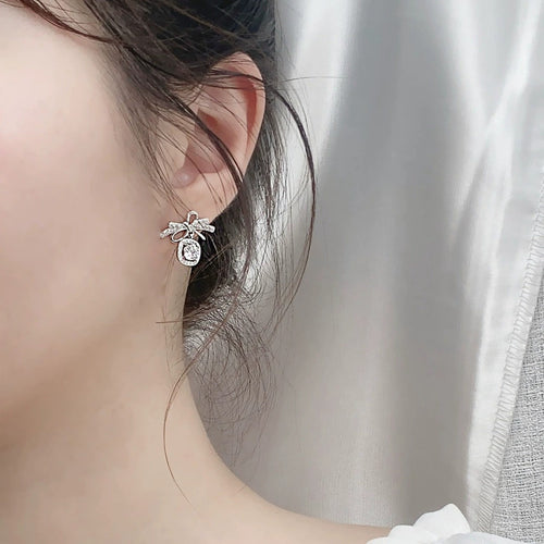 Bowknot Round Moissanite Stud Dangle Earrings with CZ in White Gold-Plated S925 sterling silver worn on ear by model showing scale, placement, and stud dangle earrings styling