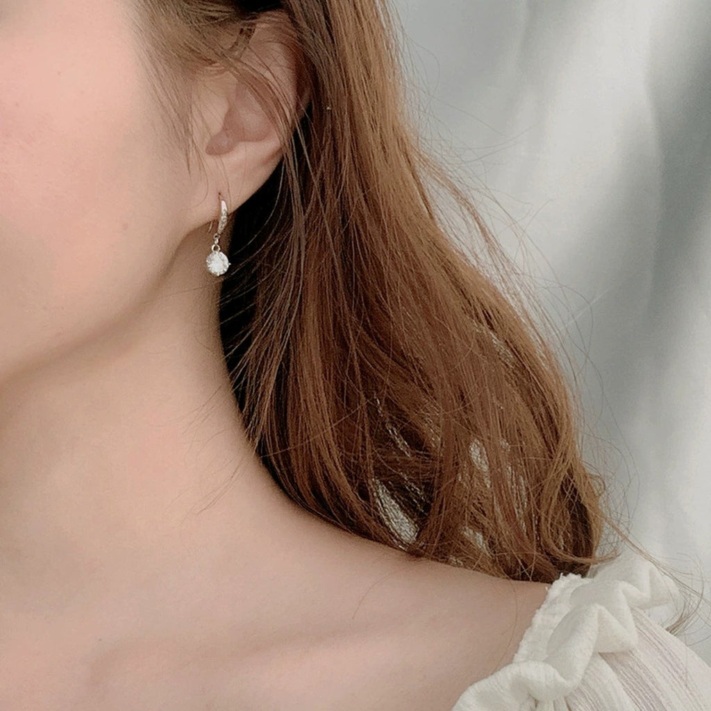 Round Moissanite Solitaire Hook Dangle Earrings in White Gold-Plated S925 sterling silver worn on ear by model showing scale, placement, and hook dangle earrings styling