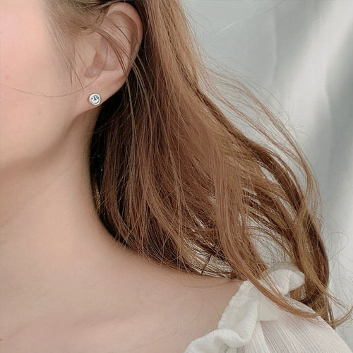 Bezel Round Moissanite Stud Earrings in White Gold-Plated S925 sterling silver worn on ear by model showing scale, placement, and stud earrings styling