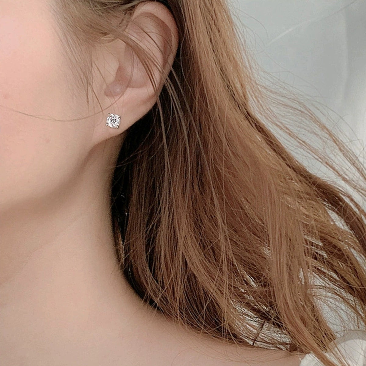 Four-Prong Round Moissanite Screw-Back Stud Earrings in White Gold-Plated S925 sterling silver worn on ear by model showing scale, placement, and stud earrings styling